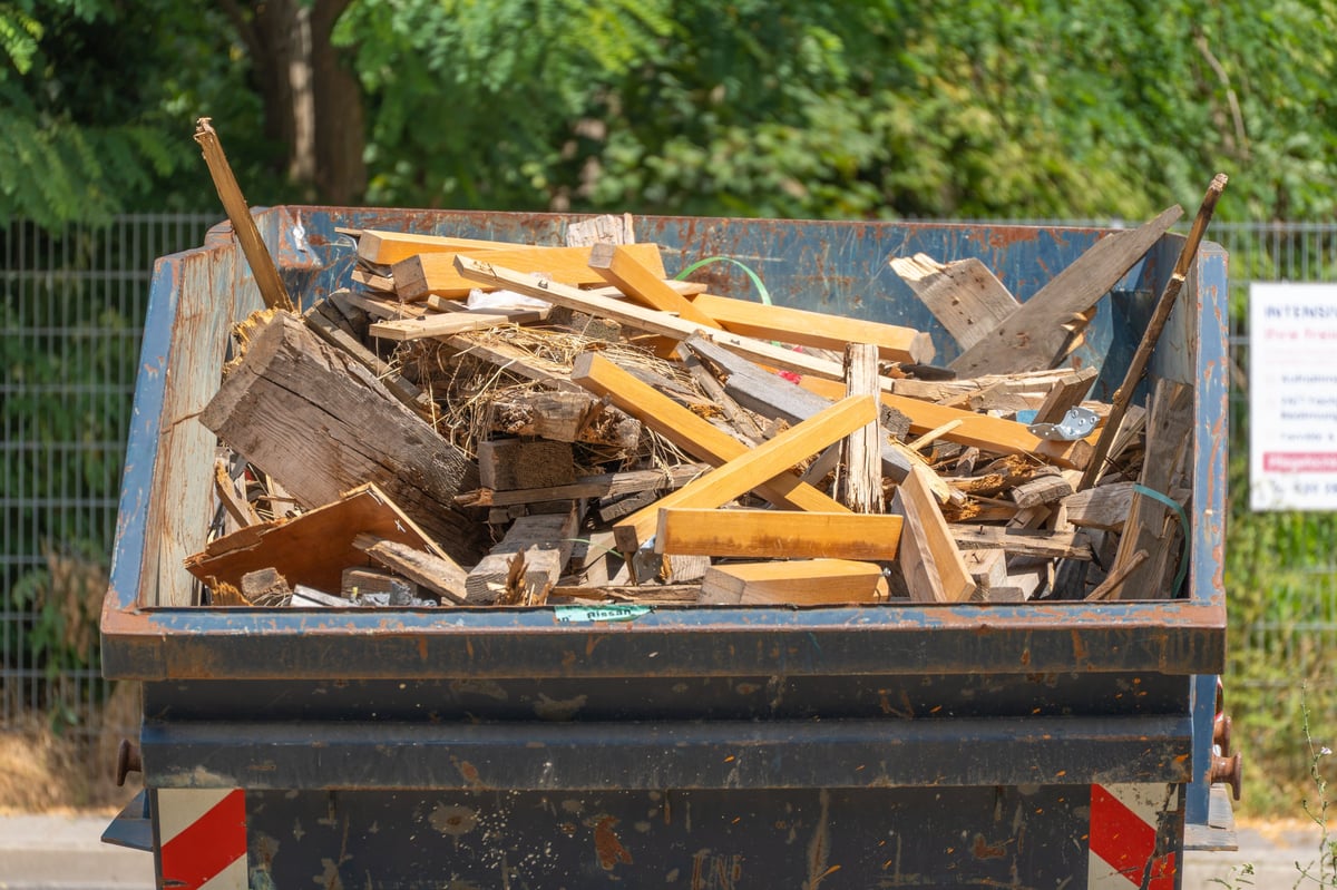Metal construction dumpster filled with broken timber and demolition debris