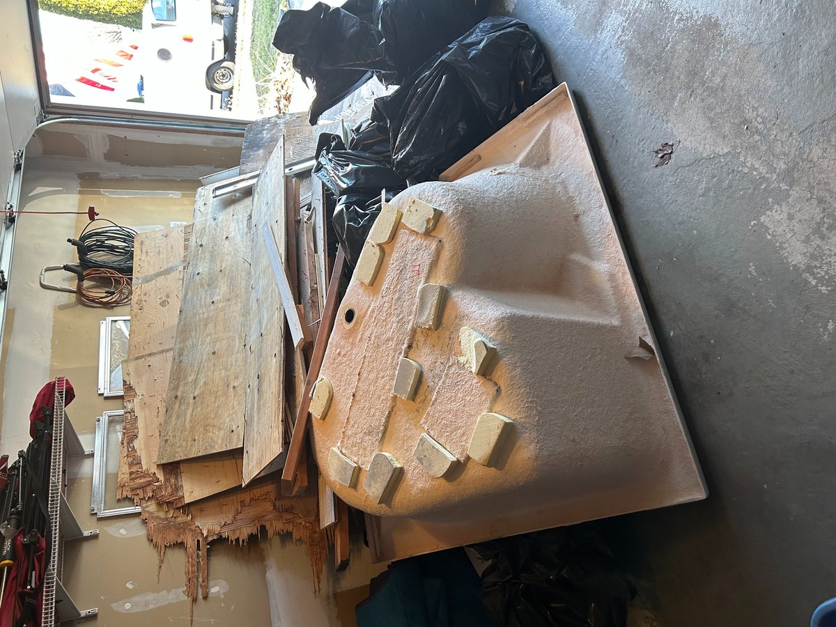 Deteriorated car interior with rust-covered metal panels and plastic trim parts stacked in a garage workshop